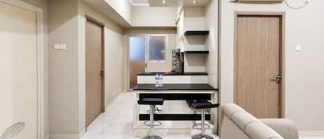 A modern kitchen with a black countertop, two bar stools, and a water dispenser.