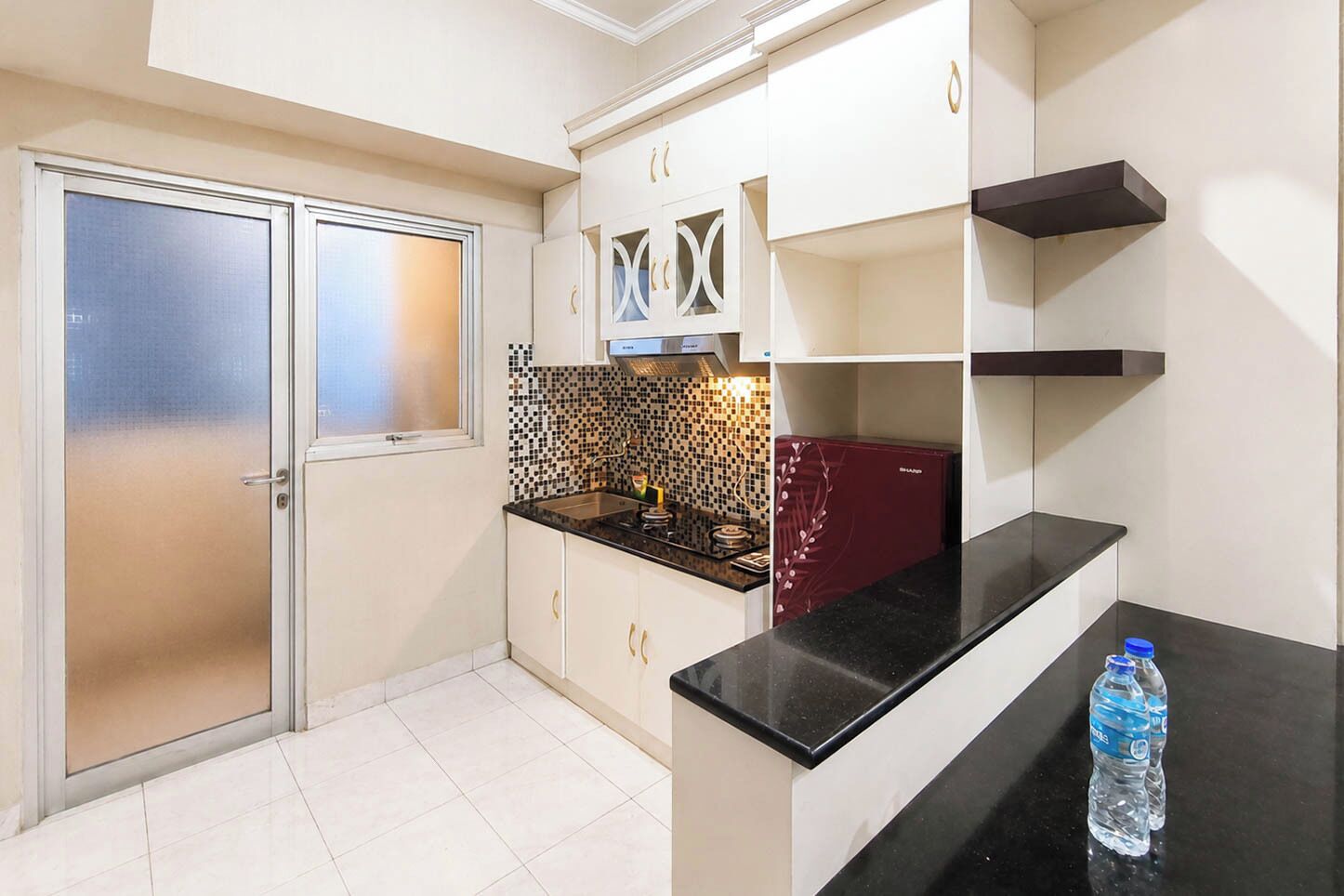 A kitchen with a black countertop, white cabinets, and a tiled backsplash.