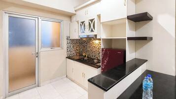 A kitchen with a black countertop, white cabinets, and a tiled backsplash.