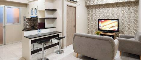 A modern living room with a sofa, a TV, and a kitchen area with a bar.