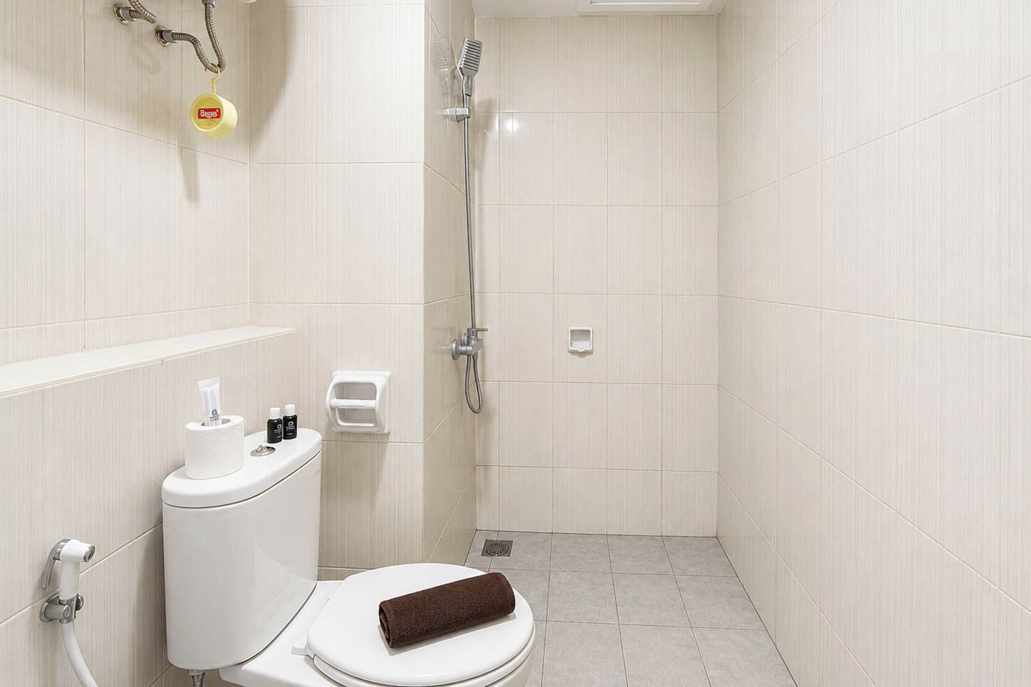 Uma casa de banho pequena e moderna, com sanita, chuveiro e um porta-toalhas.