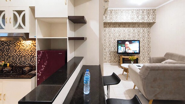 A modern kitchen with a black countertop, a red appliance, and a tiled backsplash. - Serene 2Br Apartment Newton Residence Bandung (Bandung)