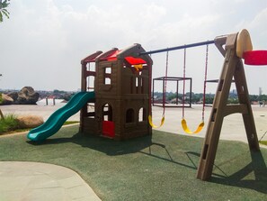 Ein Spielplatz mit Rutsche, Schaukeln und einer Kletterlandschaft.