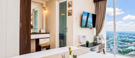 A hotel room with a large bed, a desk, a TV, and a city view.