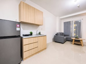A modern kitchen with a built-in refrigerator, wooden cabinets, and a small countertop with a sink. - Good Designed 2Br Apartment Woodland Park Residence (Jakarta)