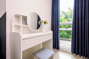A white vanity with a round mirror, a vase with flowers, and a bench. - Stunning 2Br Apartment Woodland Park Residence (Jakarta)