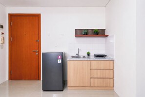 A compact kitchen with a refrigerator, a sink, and wooden cabinets. - Stunning 2Br Apartment Woodland Park Residence (Jakarta)