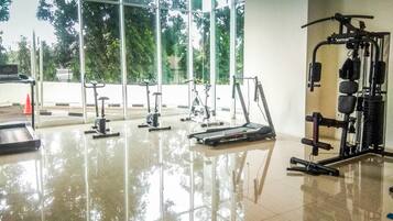 A gym with various exercise equipment, large windows, and a tiled floor.