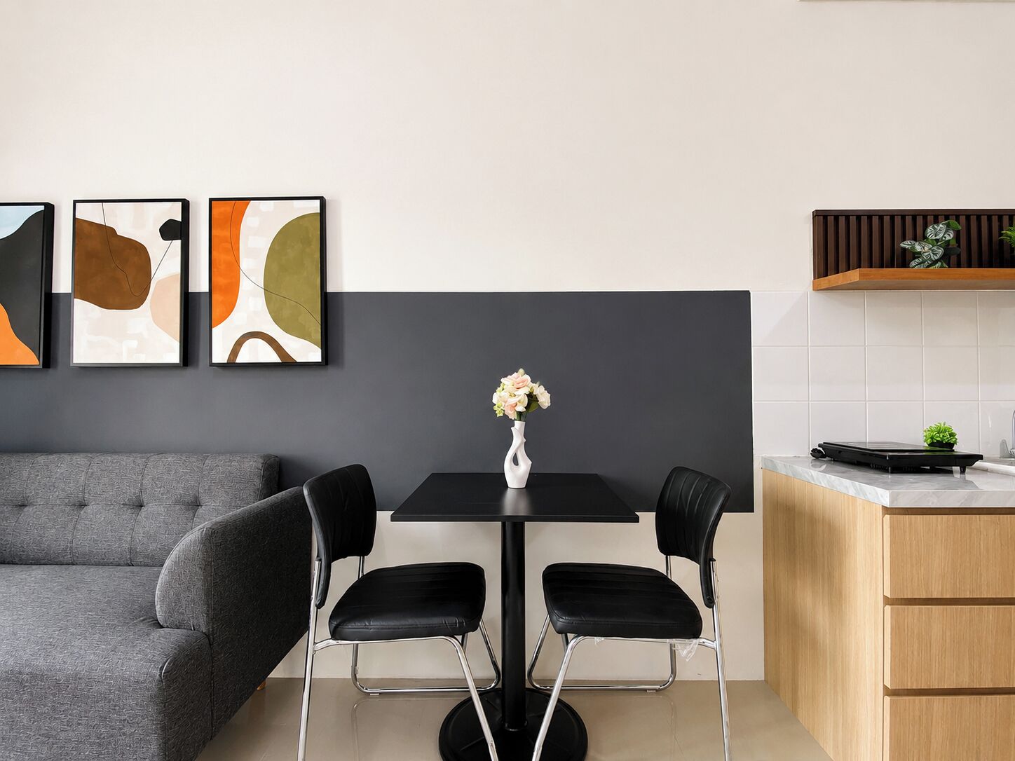 Une cuisine moderne avec une table à manger, des chaises et un vase rempli de fleurs.