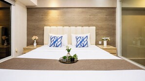 Un dormitorio moderno con una cama grande, dos mesitas de noche y una mesilla con un florero.