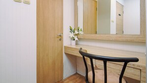 Un baño con puerta de madera, espejo, lavamanos y una silla.