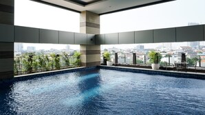 Una piscina interior moderna con vista a la ciudad, con suelo de baldosas y un balcón con asientos.