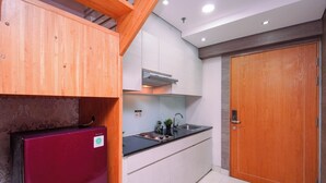 Una cocina compacta con refrigerador integrado, un lavamanos y una puerta de madera.