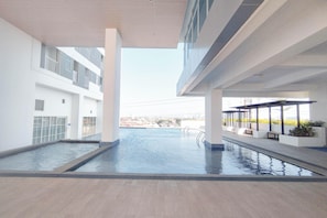 Ein moderner, überdachter Pool mit Blick auf die Stadtlandschaft, umgeben von weißen Wänden und einem gefliesten Boden.