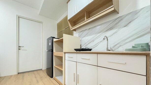 A kitchen with white cabinets, a marble backsplash, and a built-in sink. - Cozy Japandi Style 1Br At Apartment Kyo Society (Surabaya)