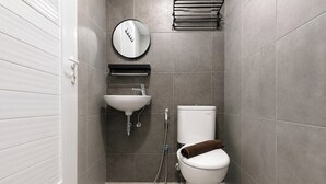 A bathroom with a toilet, sink, and a mirror. - Best Choice Studio Apartment At Westown View Surabaya (Surabaya)