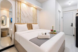 Ein modernes Hotelzimmer mit einem großen Bett, einem Nachttisch, einem Spiegel und einer Tür.