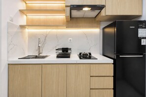 Eine moderne Küche mit einem schwarzen Kühlschrank, einem Gasherd und Holzschränken.