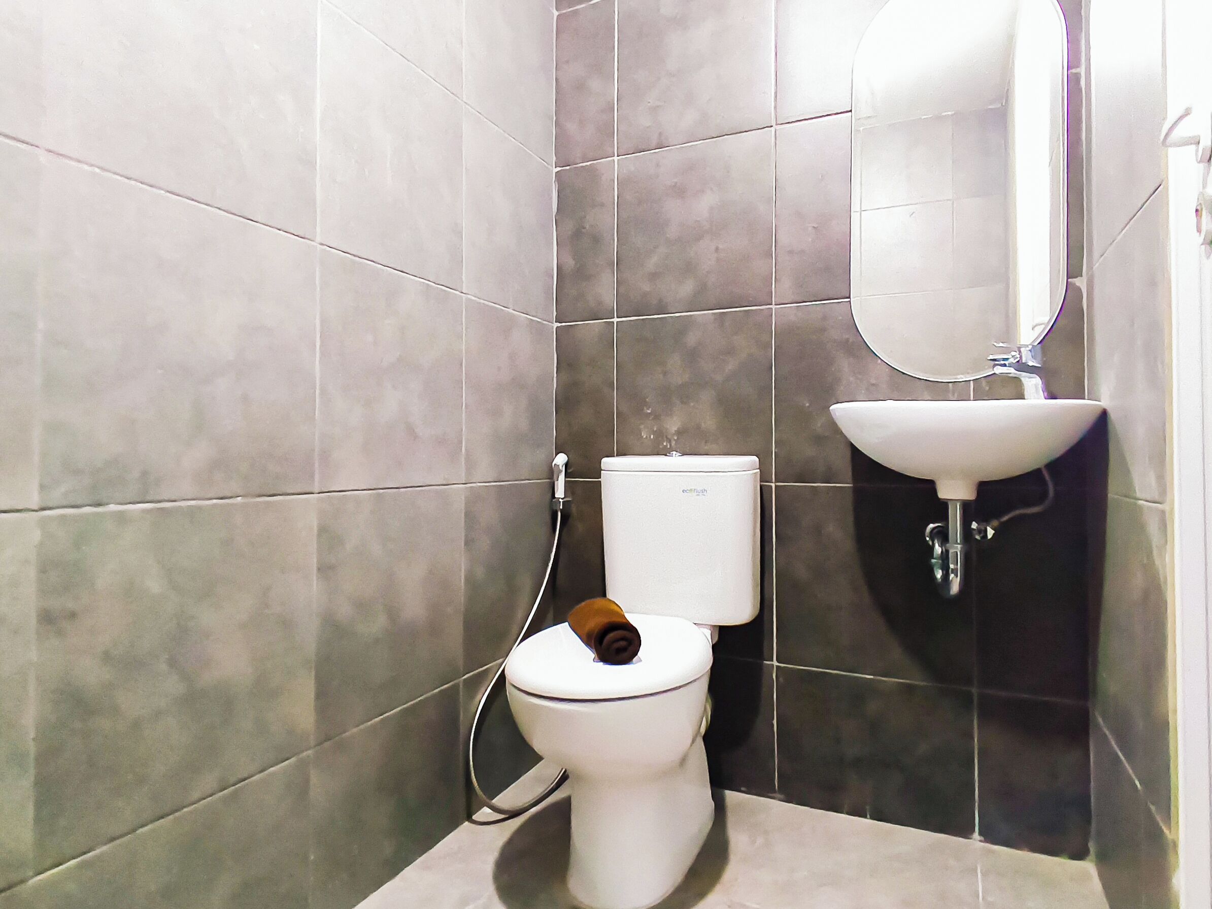 A small bathroom with a toilet, a sink, and a mirror.