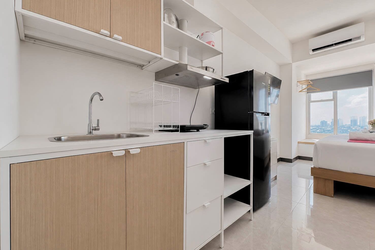 A modern kitchen with a sink, a black refrigerator, and a window with a city view.
