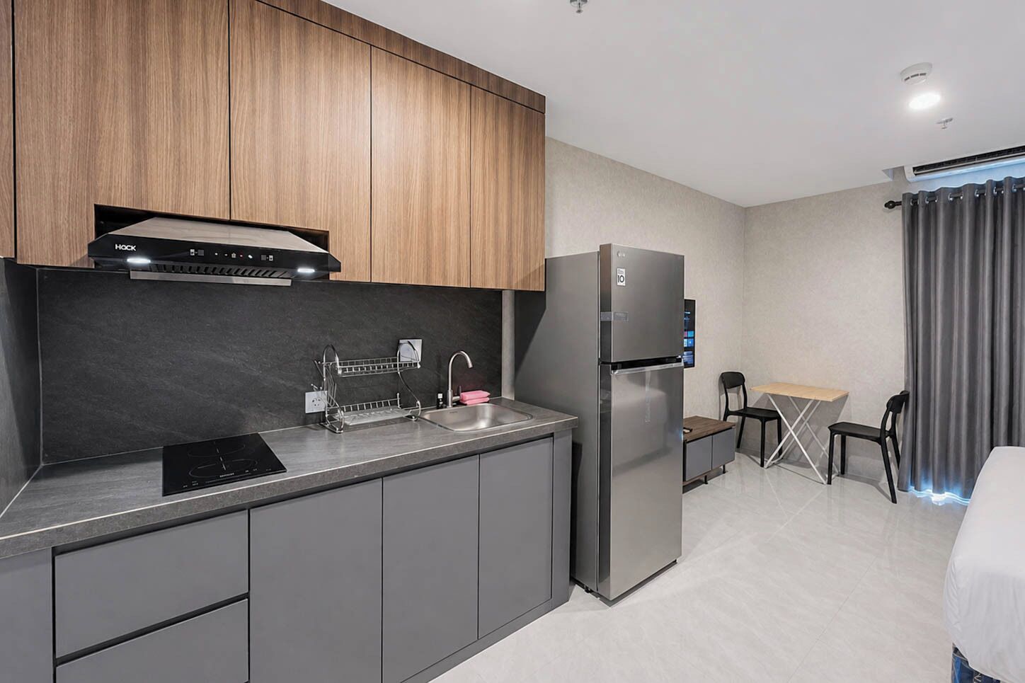 A modern kitchen with a built-in oven, a stainless steel refrigerator, and a double sink.