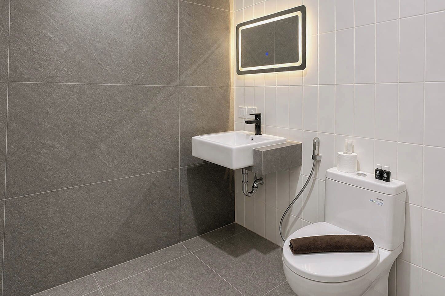 Une salle de bain moderne avec des toilettes blanches, un lavabo et un espace douche.