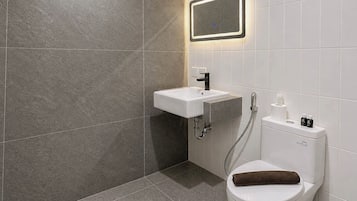 Une salle de bain moderne avec des toilettes blanches, un lavabo et un espace douche.