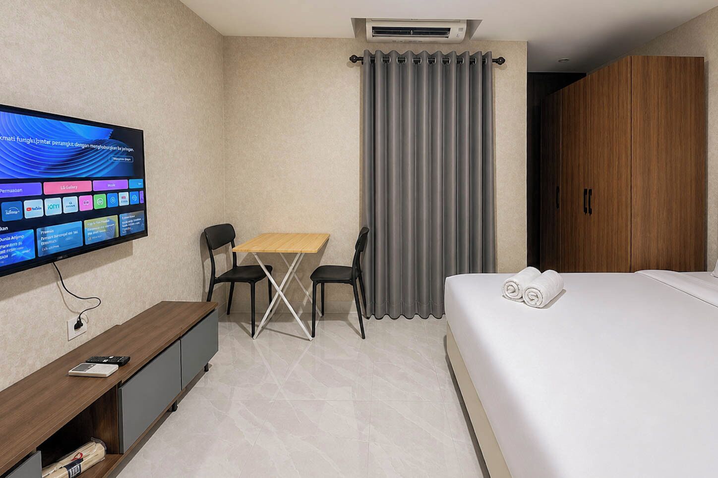 Habitación de hotel con cama, escritorio con computadora, televisor y ventana con cortinas.