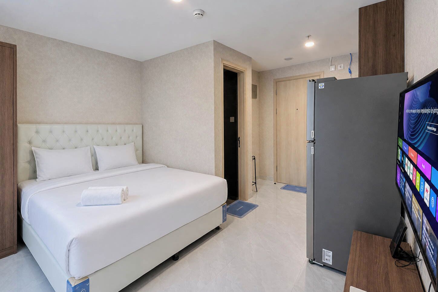 A hotel room with a large bed, a television, and a door leading to a bathroom.