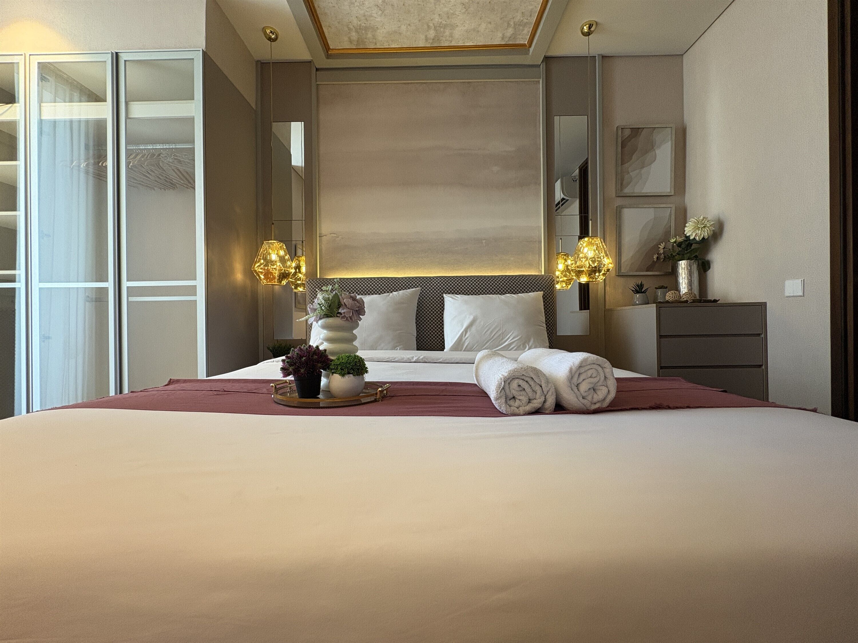Habitación de hotel con una cama grande, lámparas de noche, un tocador y un espejo.