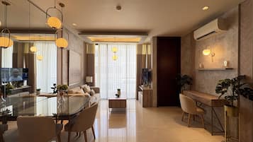 Un salón moderno con una mesa de comedor de vidrio, asientos cómodos y un ventanal con cortinas.