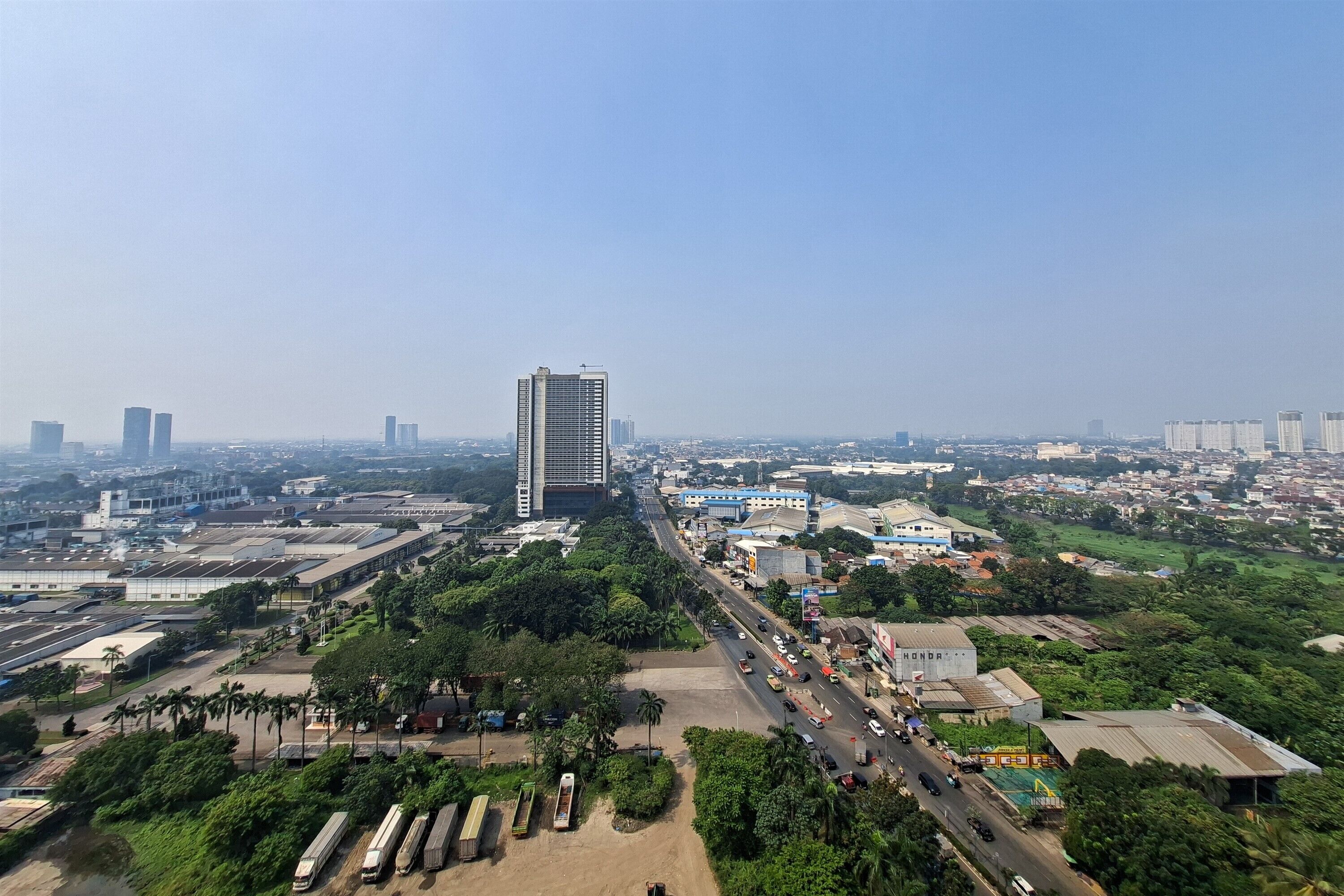 Un paysage urbain avec un gratte-ciel imposant, une rue principale et des espaces verts environnants.