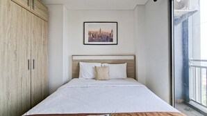 A hotel room with a bed, a framed cityscape picture, and a magazine on the bed. - Bright Comfortable Studio Room At Apartment Springwood Residence Tangerang (Tangerang)