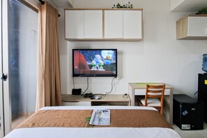A hotel room with a bed, a desk with a chair, a television mounted on the wall, and a wardrobe. - Bright Comfortable Studio Room At Apartment Springwood Residence Tangerang (Tangerang)