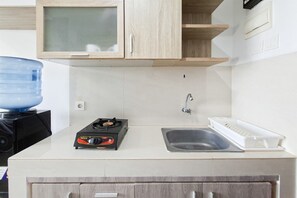 A kitchen with a gas stove, a sink, and a water dispenser. - Bright Comfortable Studio Room At Apartment Springwood Residence Tangerang (Tangerang)