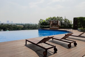 A rooftop pool with two sun loungers and a view of the city skyline. - Bright Comfortable Studio Room At Apartment Springwood Residence Tangerang (Tangerang)