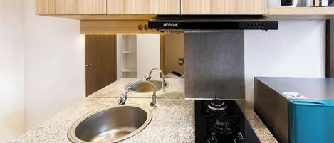 A kitchen with a stainless steel sink, a gas stove, and wooden cabinets.