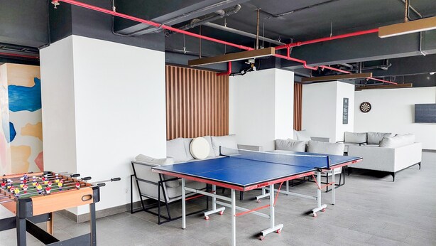 A modern indoor space with a foosball table, ping pong table, and sofas. - Skyline View 1Br Without Living Room At Apartment Bintaro Embarcadero (Tangerang)