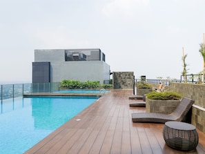 A rooftop pool area with a modern building, lounge chairs, and a view of the city. - Skyline View 1Br Without Living Room At Apartment Bintaro Embarcadero (Tangerang)