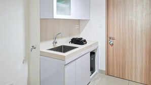A compact kitchenette with a sink, a stove, and a cabinet. - Skyline View 1Br Without Living Room At Apartment Bintaro Embarcadero (Tangerang)