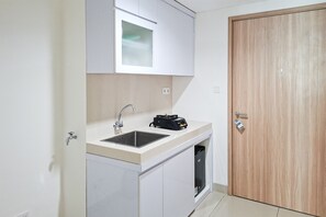 A compact kitchenette with a sink, a stove, and a cabinet.