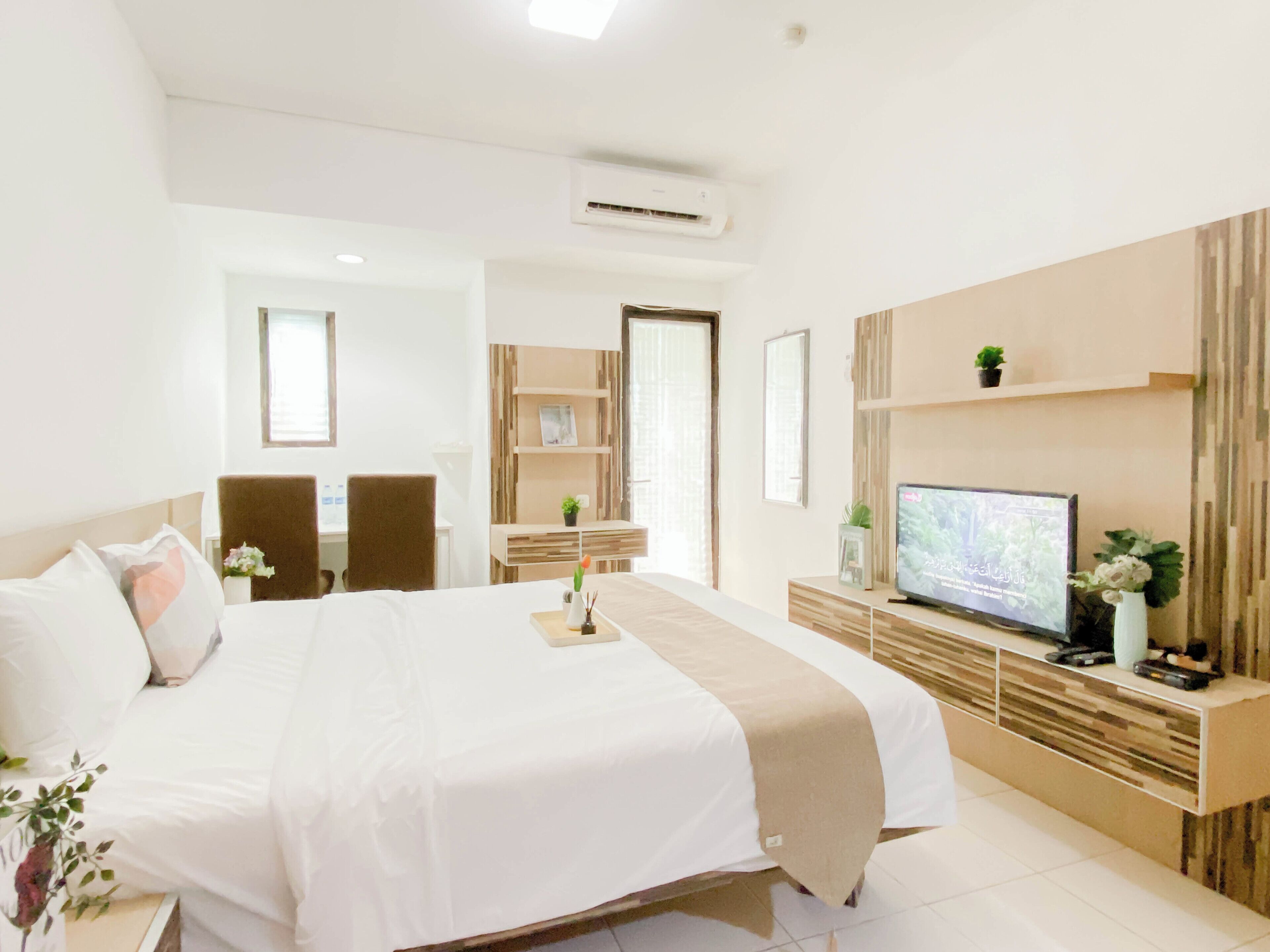 A hotel room with a bed, a TV, a desk, and a chair.