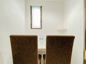 Ein Zimmer mit zwei braunen Sesseln, die ein Tisch mit zwei Wasserflaschen gegenüber stehen.