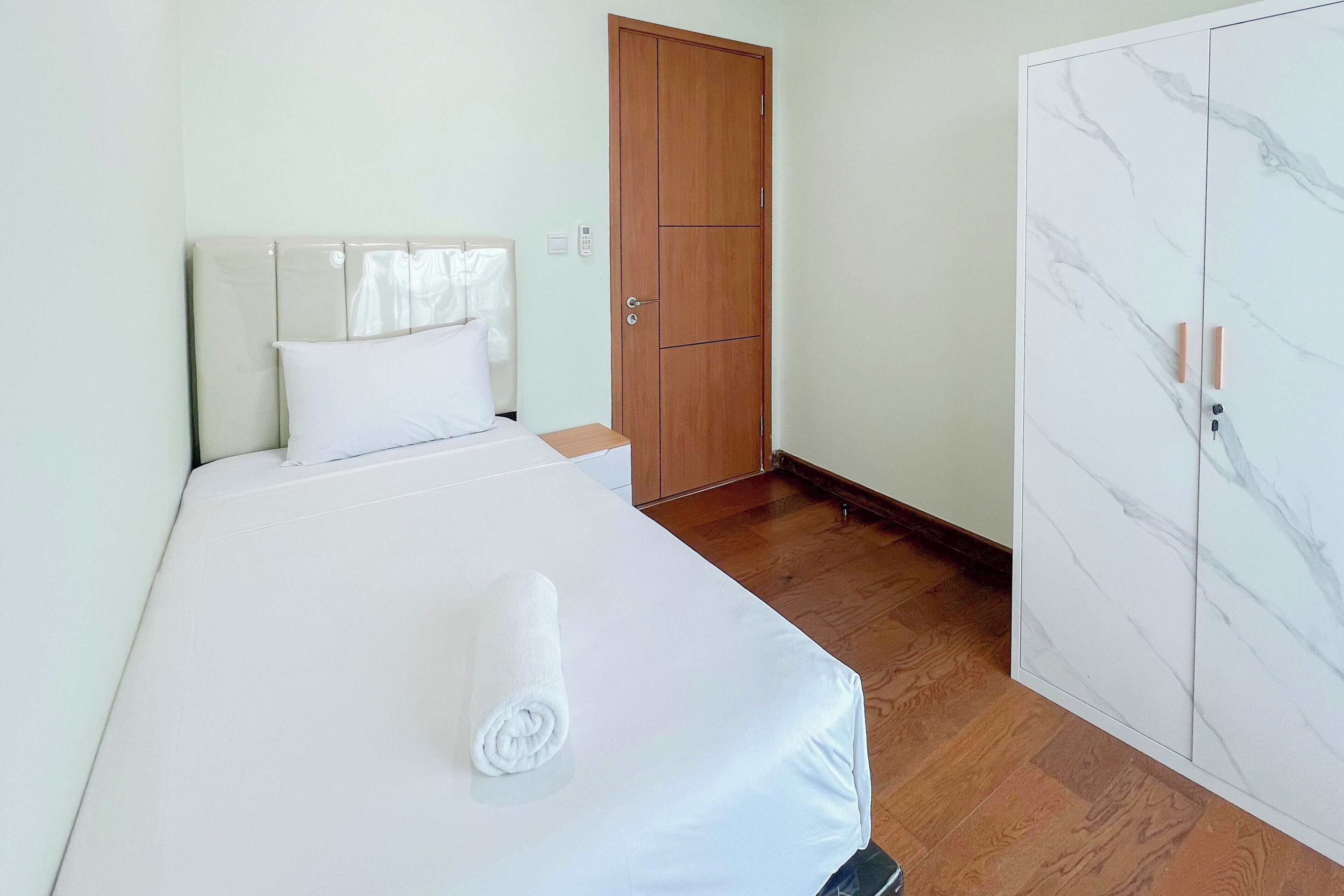 A hotel room with a bed, a wooden wardrobe, and a marble-patterned cabinet.