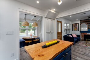 Cozinha moderna com ilha de madeira, luminárias pendentes e vista para o exterior.
