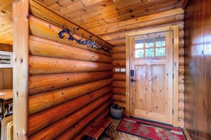 A log cabin interior with wooden walls, a door with windows, a bench, and a rug. - 2.5 Acre Log Cabin, Cascade Views, Dog-Friendly (Bend)