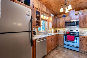 Eine Küche mit Holzausstattung, einem Edelstahlkühlschrank, einer Mikrowelle und einem Backofen.
