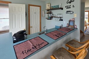 A kitchen with a bar area, a coffee machine, and a sign that says 'Coffee Tea & The Bar'. - 7853 - Anchor Management Spacious 6BR, 5.2BA oceanside home in Frisco for up to 12 guests. (Frisco)