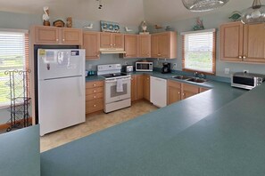 Eine Küche mit Holzschränken, einem Kühlschrank, einer Mikrowelle, einem Backofen, einem Geschirrspüler und einem Toaster.