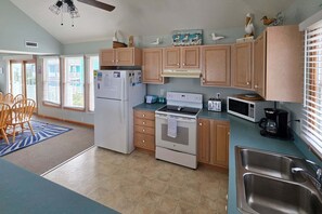 A kitchen with wooden cabinets, a refrigerator, a stove, a microwave, and a sink. - 7853 - Anchor Management Spacious 6BR, 5.2BA oceanside home in Frisco for up to 12 guests. (Frisco)